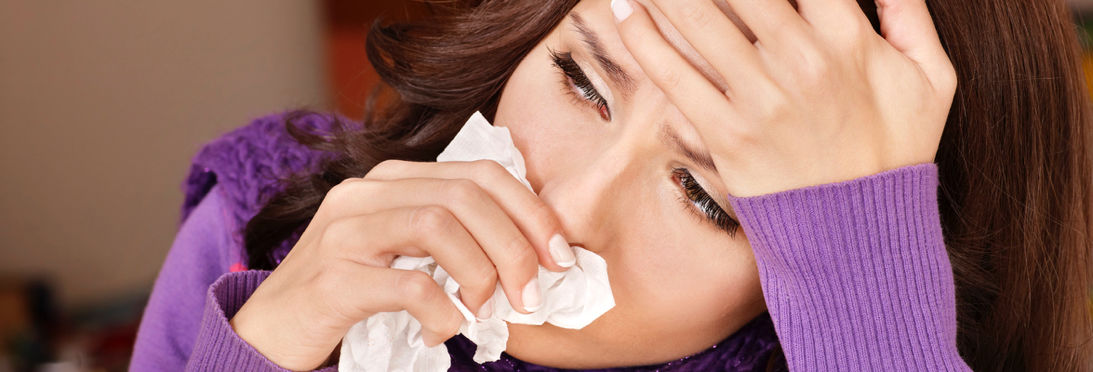 Woman with a cold holding a kleenex to her nose