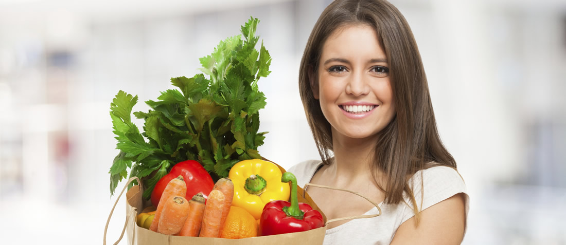A woman holding a bag of fresh vegetables