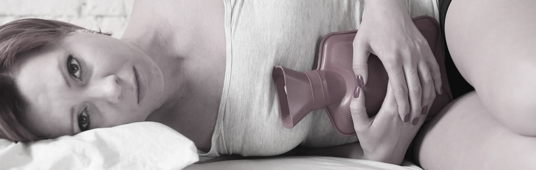 A woman laying on her side holding a hot water bottle over her belly