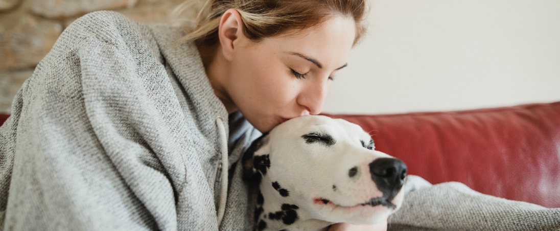A woman kissing her dalmatian dog on the head