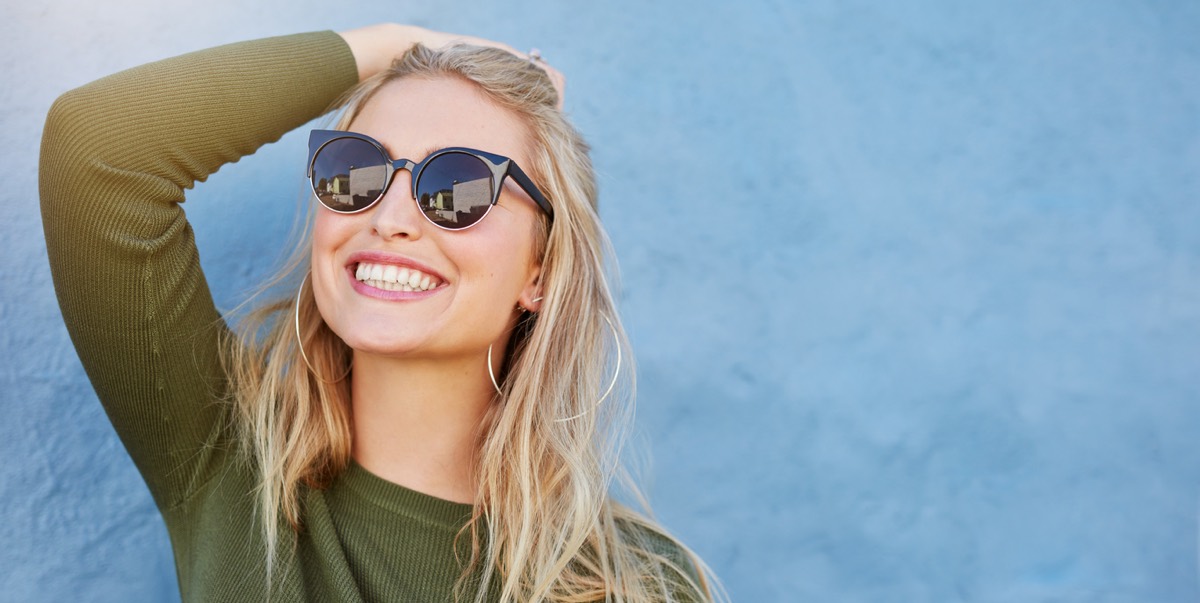 Twenty Something Woman Wearing Sunglasses and Smiling Confidently